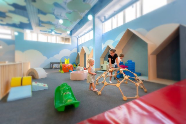 Kleinkinder spielen im Wolkenland mit weichen Matten, Klettergerüst und Wolkendekoration