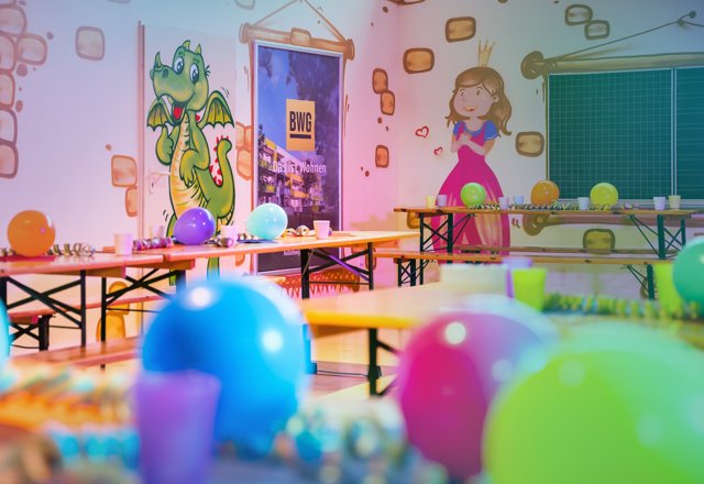 Gruppe fröhlicher Kinder feiert Kindergeburtstag mit bunten Luftballons und Dekoration